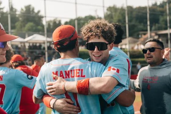 Abbotsford Cardinals players celebrate with a flag over their shoulders.