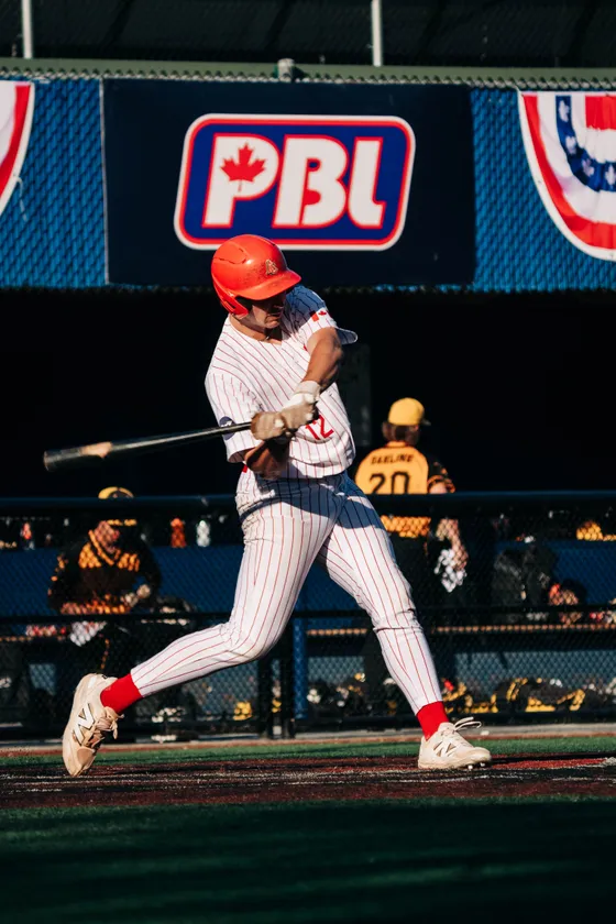 An Abbotsford Cardinals batter mid-swing under the lights.