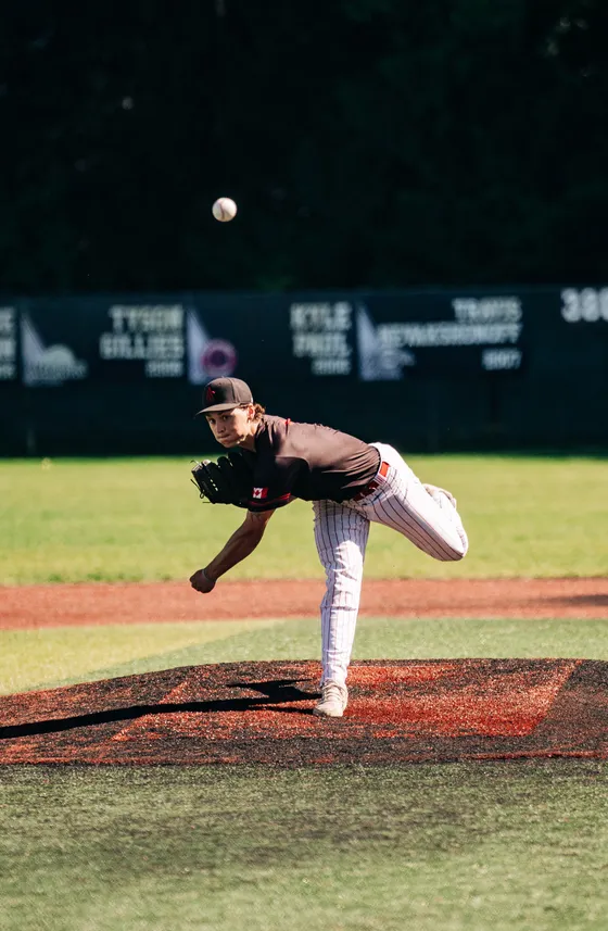 An Abbotsford Cardinals pitcher mid-delivery on a green field.