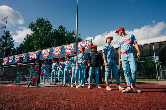 The Abbotsford Cardinals stand along the line with bunting behind them.